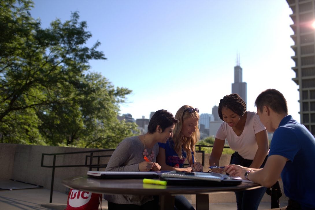 Students sitting atop of the SSB deck, with the city skyline behind them